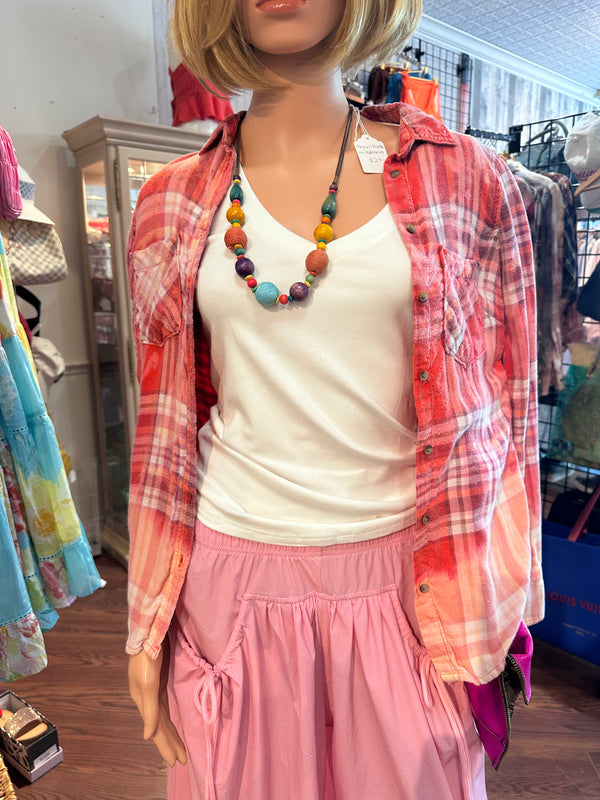 Mannequin wearing a red plaid shirt, white top, and pink pants in a store setting.